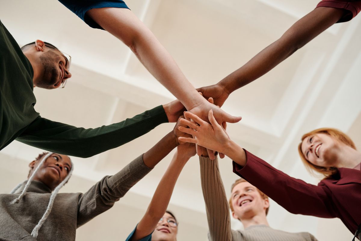 Grupo diverso de empresarios uniendo las manos en círculo, representando una comunidad que se apoya entre sí